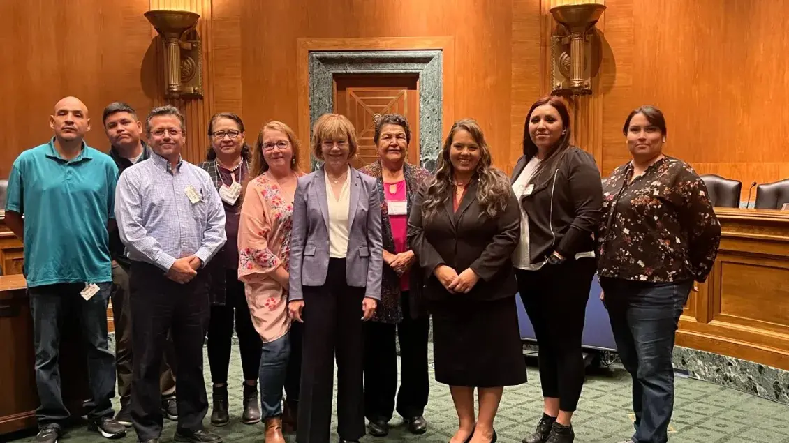 A group of people pose inside a Senate hearing room