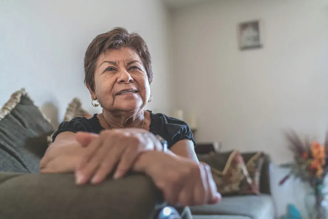 Woman with hands folded sitting on couch