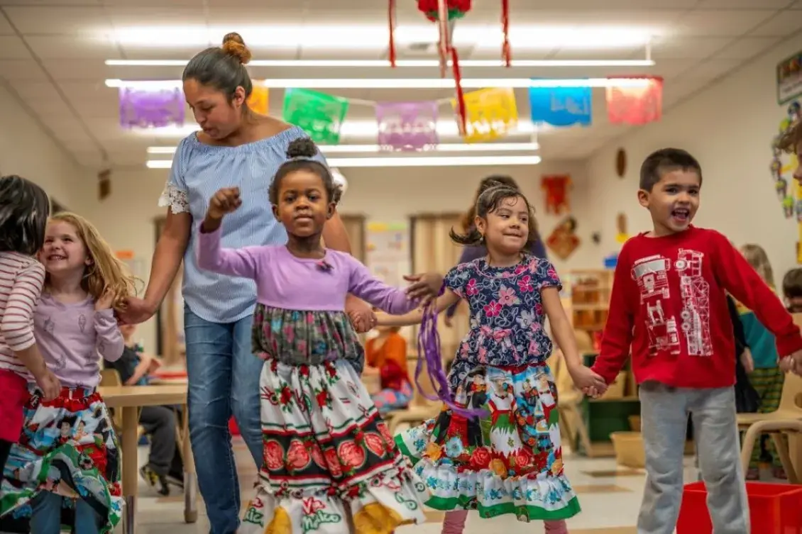 Children in brightly colored clothing dancing in classroom.