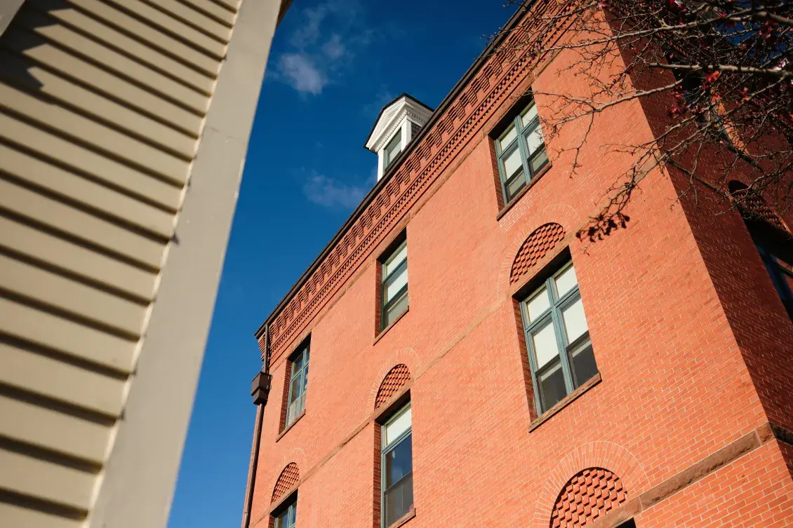 Exterior of red-brick building adjacent to tall sandstone building