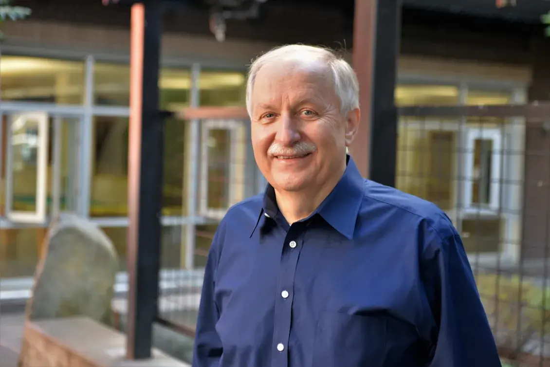 Smiling man in blue shirt standing in front of housing