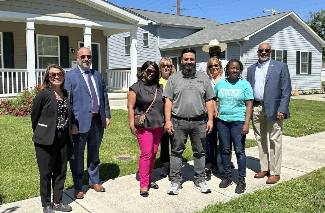 Group of smiling people standing in front of new homes