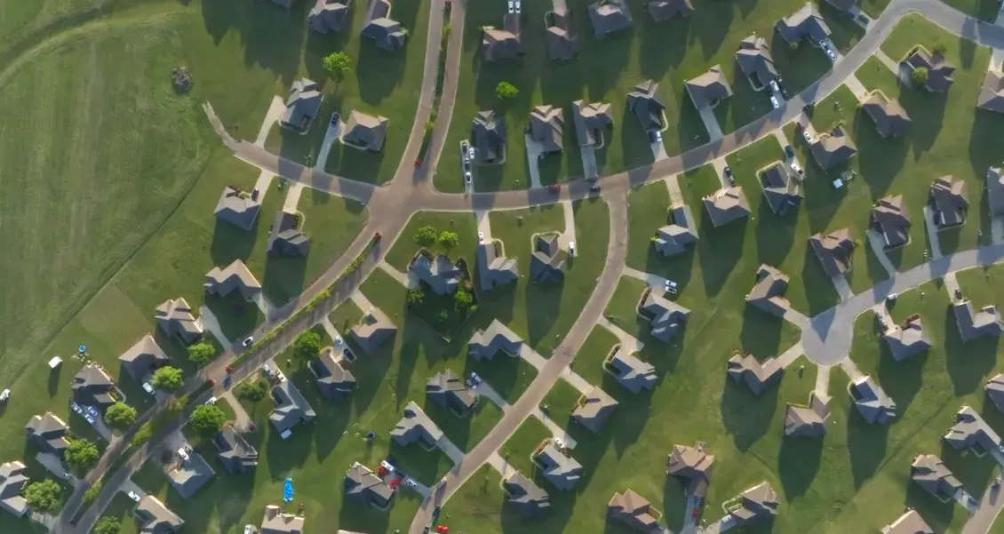 An aerial view of single-family homes and green lawns