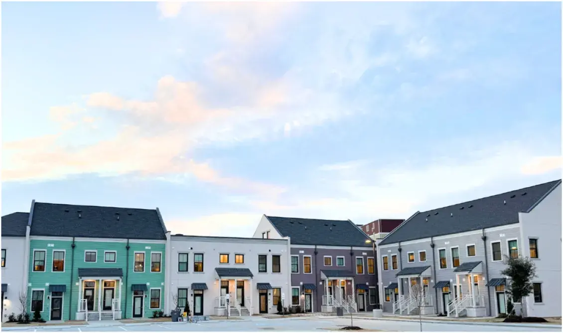row of multicolored townhomes with a light blue sky with pinkish clouds overhead