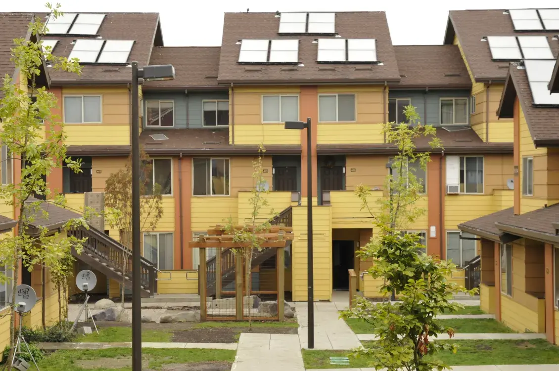 Multifamily housing development in golden hues with greenery and solar panels on the roofs