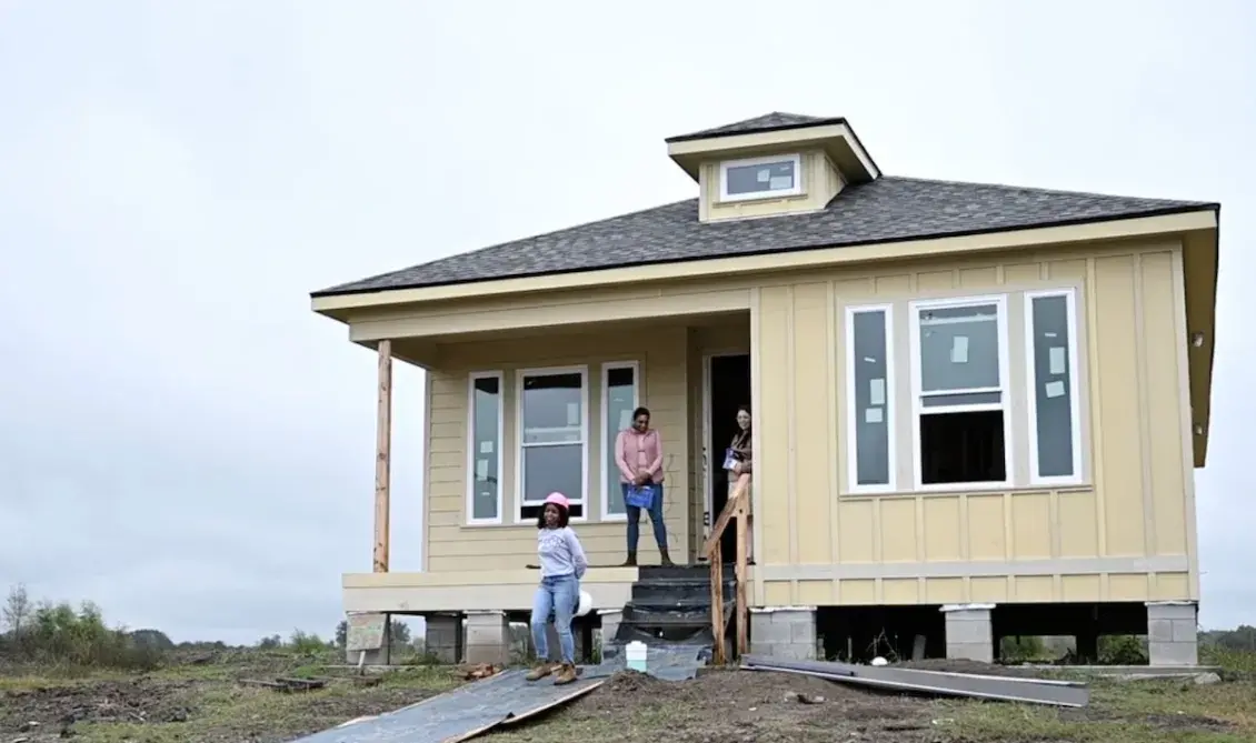 Construction workers walking out of yellow house being built