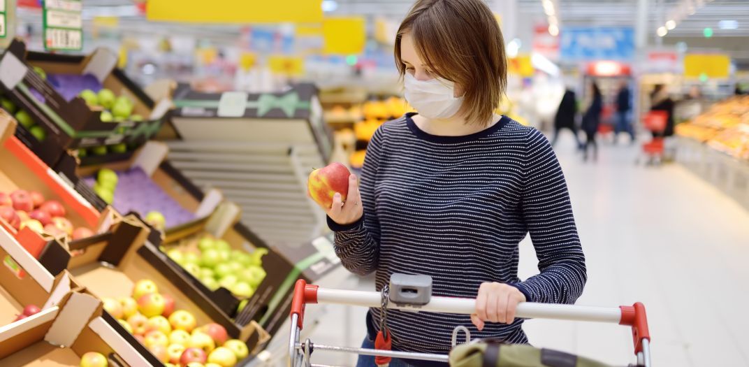 Woman with mask shopping in fruit section of grocery store