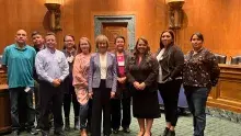 A group of people pose inside a Senate hearing room