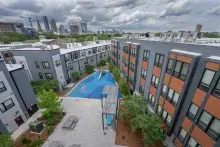 Rooftop view of multifamily housing development showing a courtyard, playground, and a blue sky and white puffy clouds overhead 