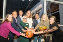 Photo of People Standing in a Semi-Circle With Hands on a Basketball