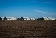 Long shot of rows of duplex apartments with a field of grass in the foreground.