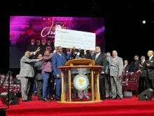 Group on a stage hold an oversized check