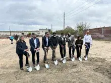 Eight people with shovels at housing groundbreaking.