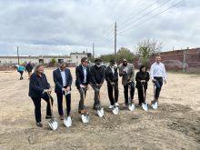 Eight people with shovels at housing groundbreaking.