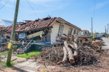 Home destroyed by hurricane surrounded by downed trees
