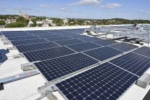 Three rows of rooftop solar panels with leafy Washington, D.C. stretching out in the distance.