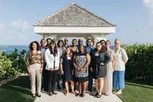 A group of people stand in front of a gazebo overlooking the ocean