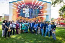 A group of individuals posing for a photo in front of a mural