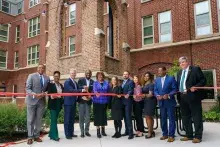 Smiling people in business suits cutting red ribbon