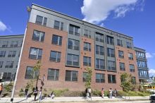 Four-story brick multifamily housing building with blue sky in the background