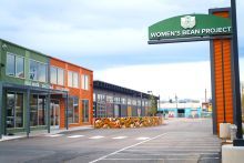 Green and orange 2-story building with a sign on the right that reads, Women's Bean Project