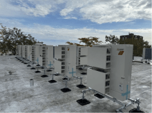 A row of rooftop heat pumps with a blue sky in the background