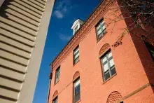 Exterior of red-brick building adjacent to tall sandstone building