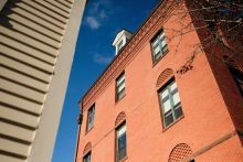 Exterior of red-brick building adjacent to tall sandstone building