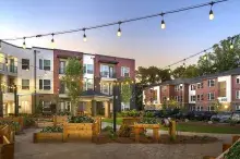 Courtyard of housing development at dusk with string lights and raised garden boxes