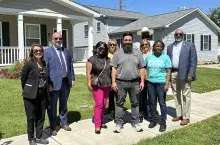 Group of smiling people standing in front of new homes