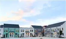 row of multicolored townhomes with a light blue sky with pinkish clouds overhead
