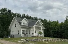Yellow two-story house surrounded by a green yard and trees