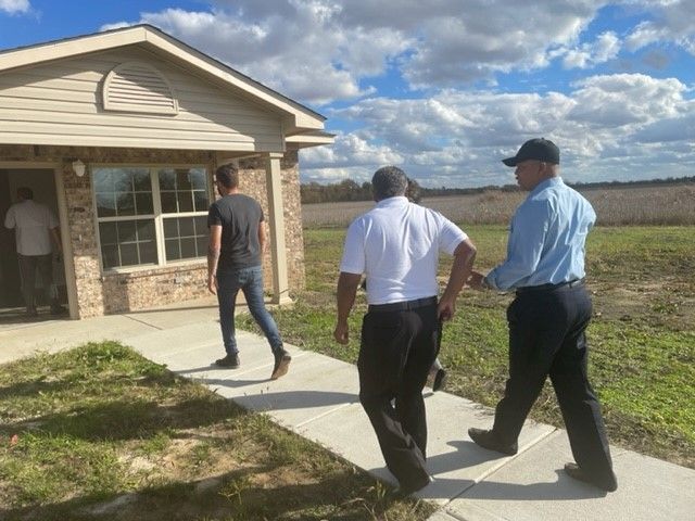Three men walk up to a house