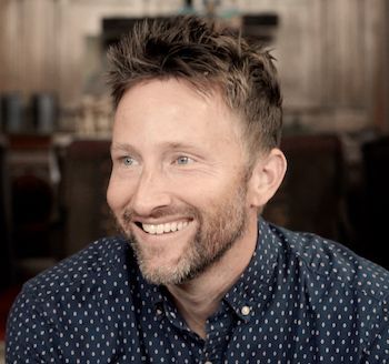 Man in a blue and white dress shirt smiling