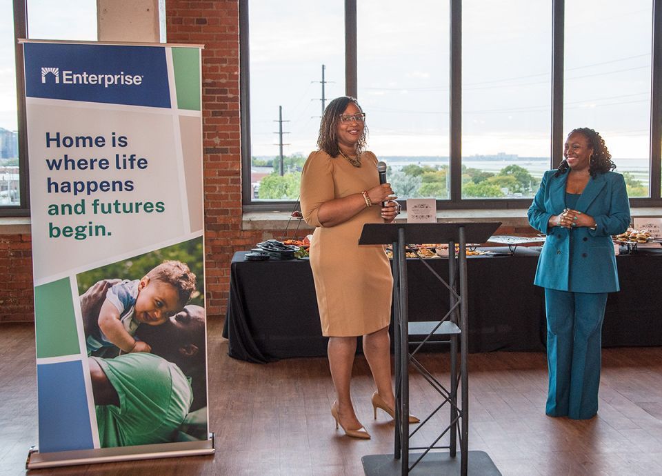 Two women stand behind a podium speaking