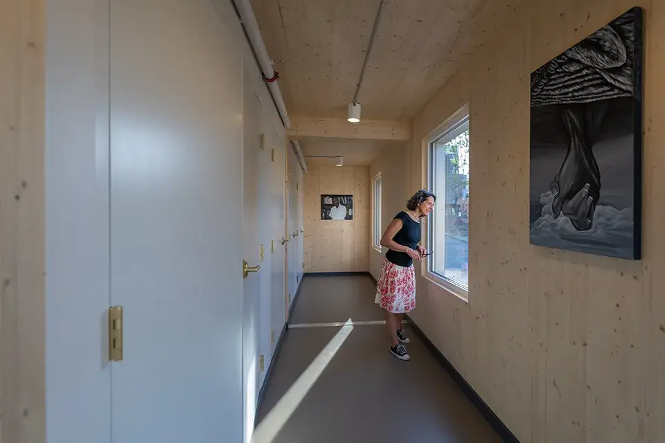 Woman stands in hallway looking out the window