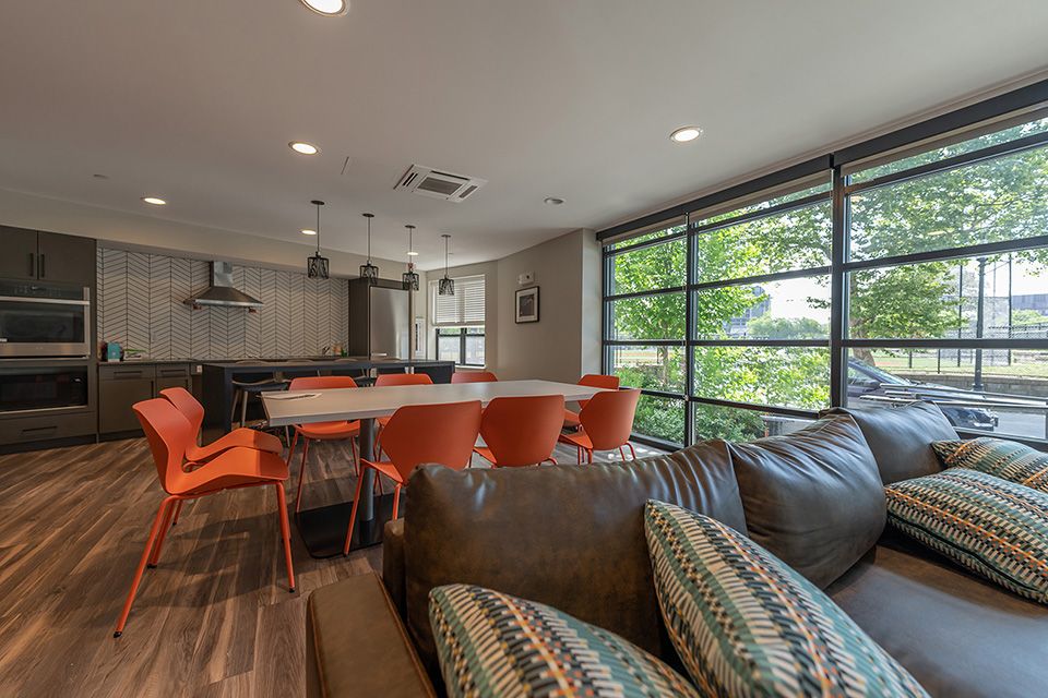 A living room and kitchen in a home with a dining table and orange chairs