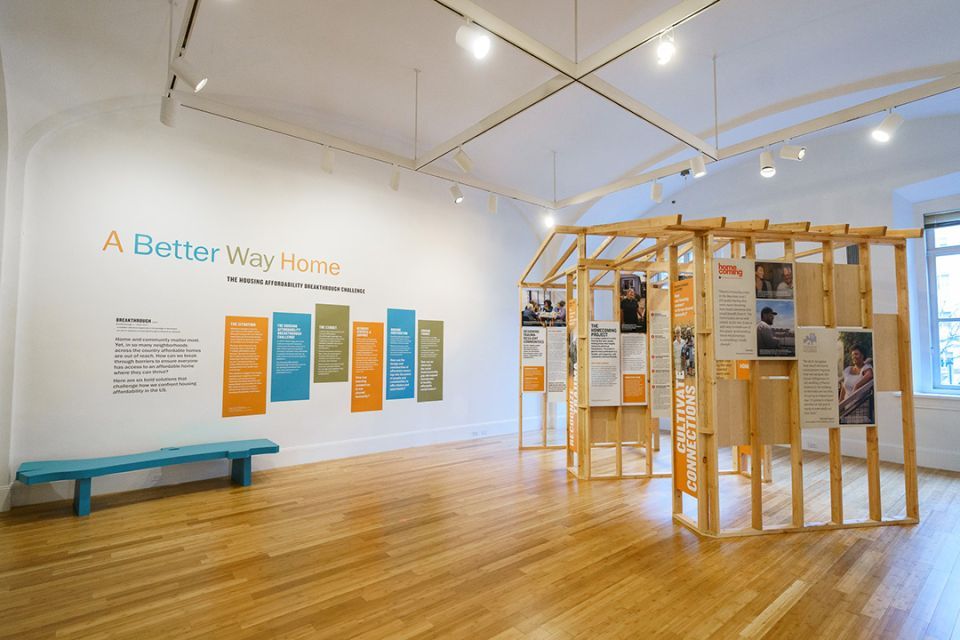 Wooden model structure exhibit with the words A Better Way Home on the wall
