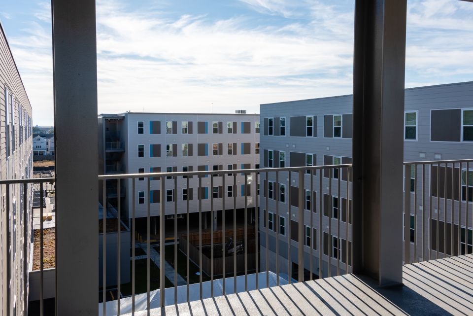 Views of a multifamily housing development from an elevated walkway with a blue sky in the background.
