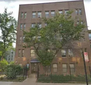 Front entrance of a 5-story apartment building with trees in front
