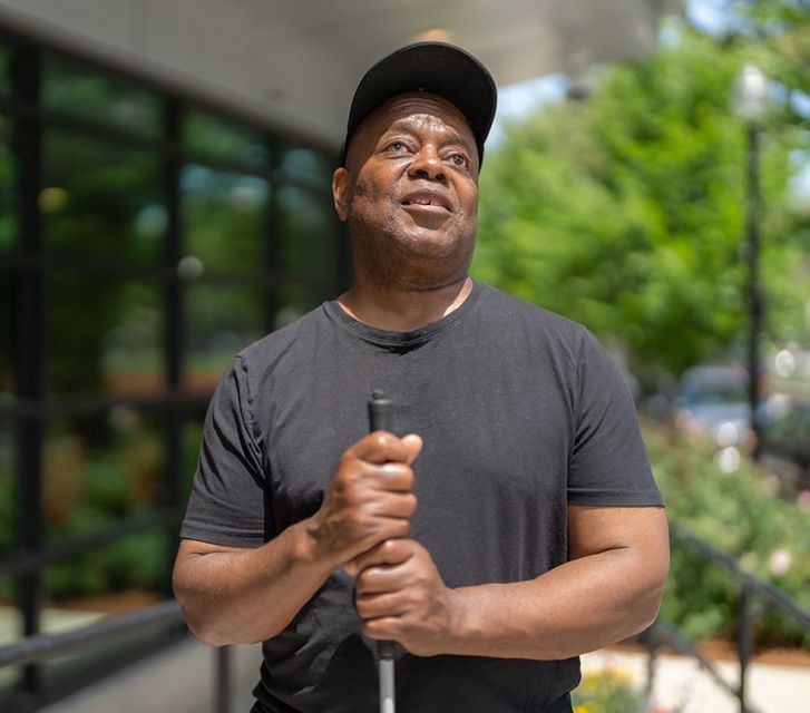 A man holds the top part of a cane as he looks upward