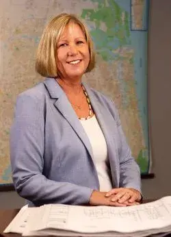 Portrait of a professional woman with a neat blonde bob and a friendly smile.