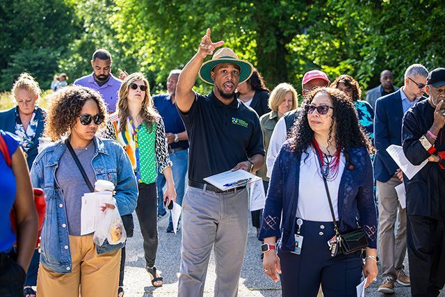 A group of people walking with a tour guide as he points forward above his head