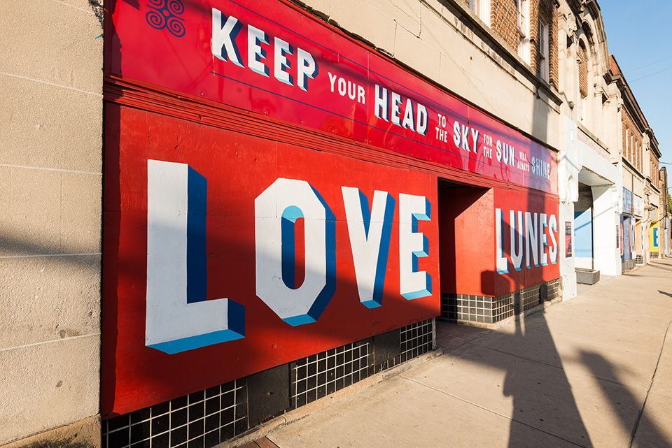 A red and white wall mural that reads keep your head to the sky and love lunes