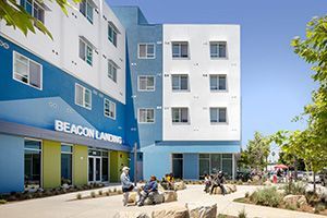 Entrance of Beacon Landing with residents sitting outside on the plaza