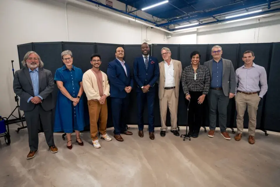 A diverse group of nine professionals standing and smiling at the camera.
