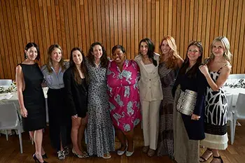 A group of women standing in front of wood-paneled wall