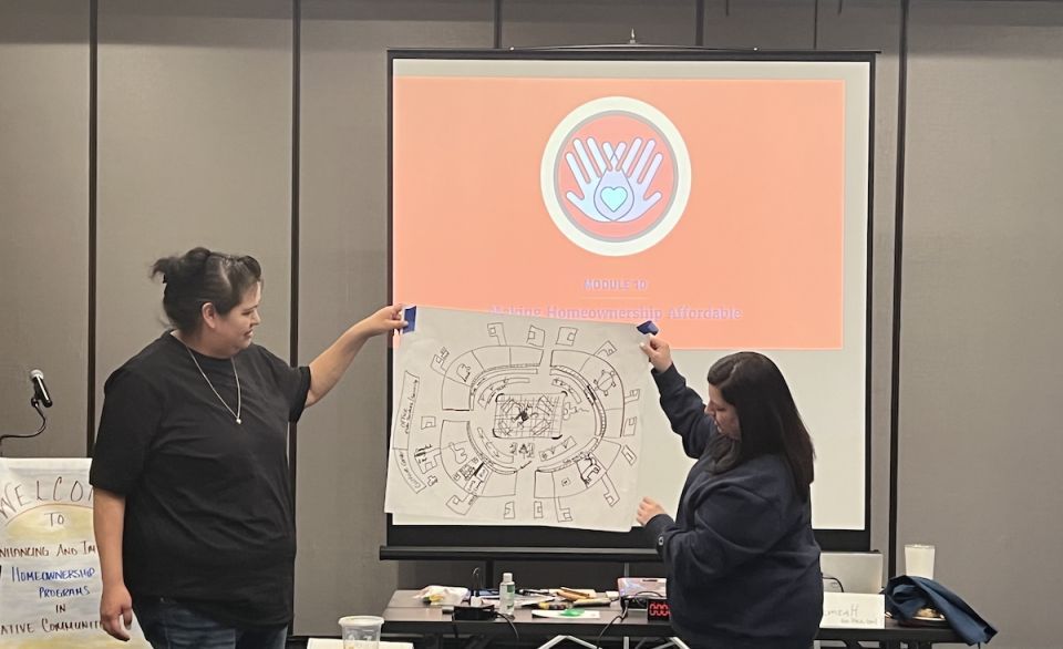 Two women holding up poster paper of a housing site map