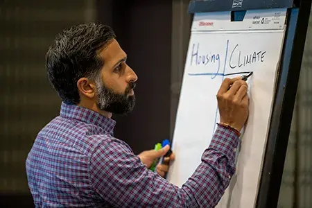 A man writes on paper on an easel