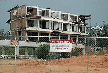 An apartment building devastated by Hurricane Katrina with a no trespassing fence in front of it